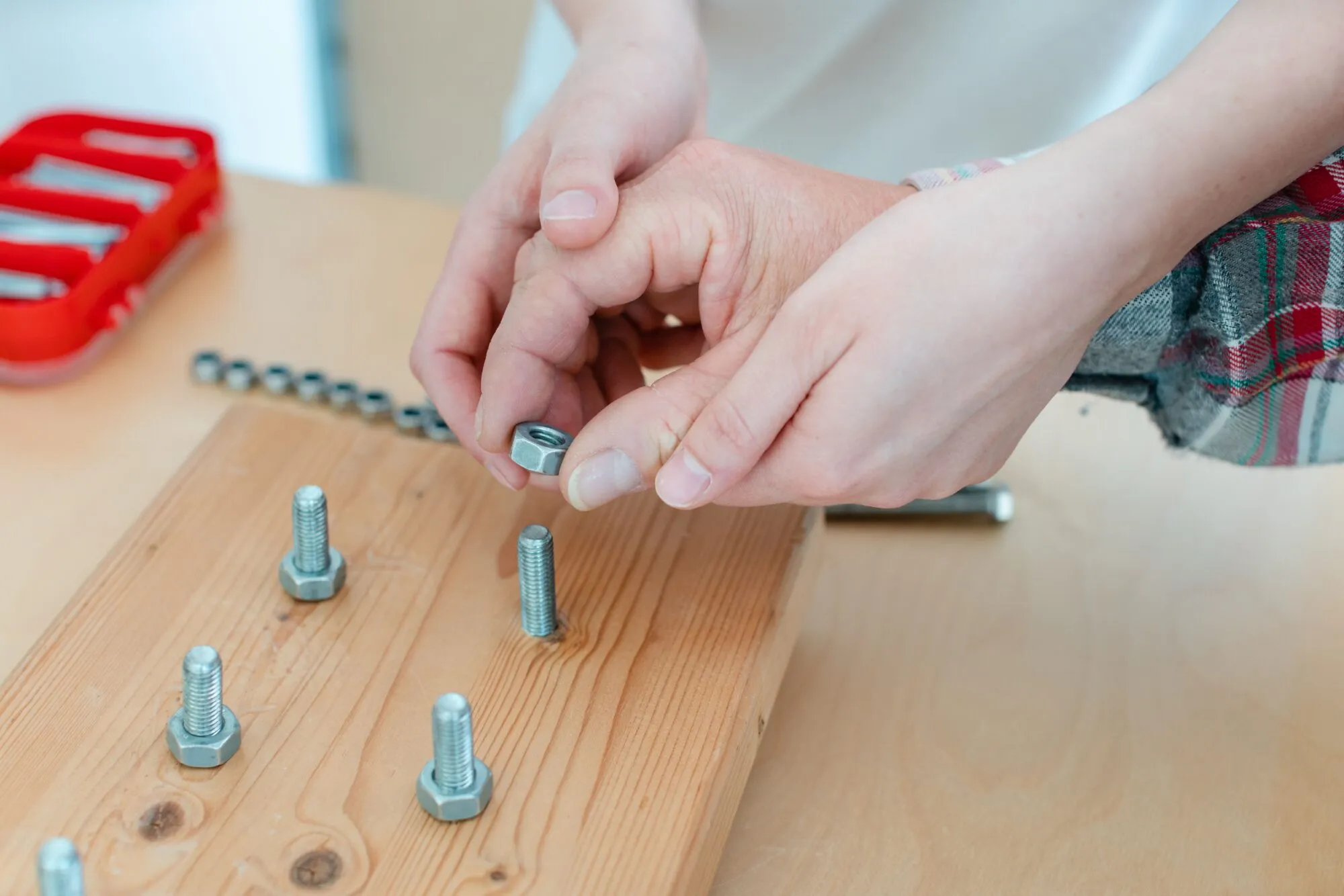 Nahaufnahme des Menschen in der Arbeitstherapie mit Schraubenmutter auf Bolzen